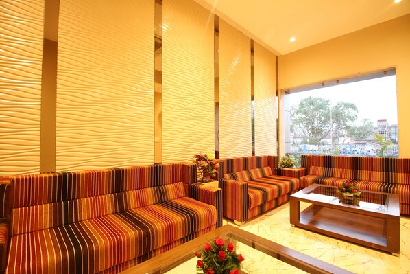 A modern living room with striped sofas, a glass coffee table, and a view of the city through large windows.