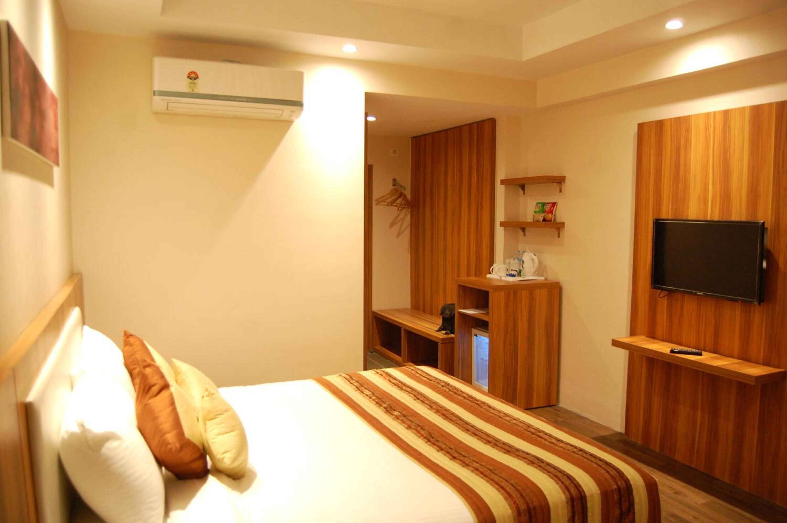 Una habitación de hotel con cama, televisor, armario y escritorio.