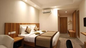 Una habitación de hotel moderna con una cama grande, mesitas de noche, una silla, un aire acondicionado y un televisor.