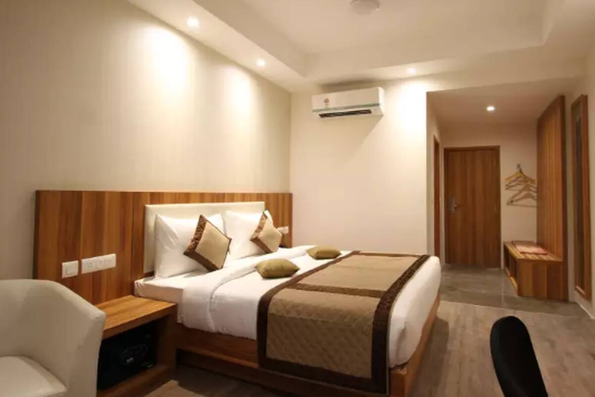 Una habitación de hotel moderna con una cama grande, mesitas de noche, una silla, un aire acondicionado y un televisor.