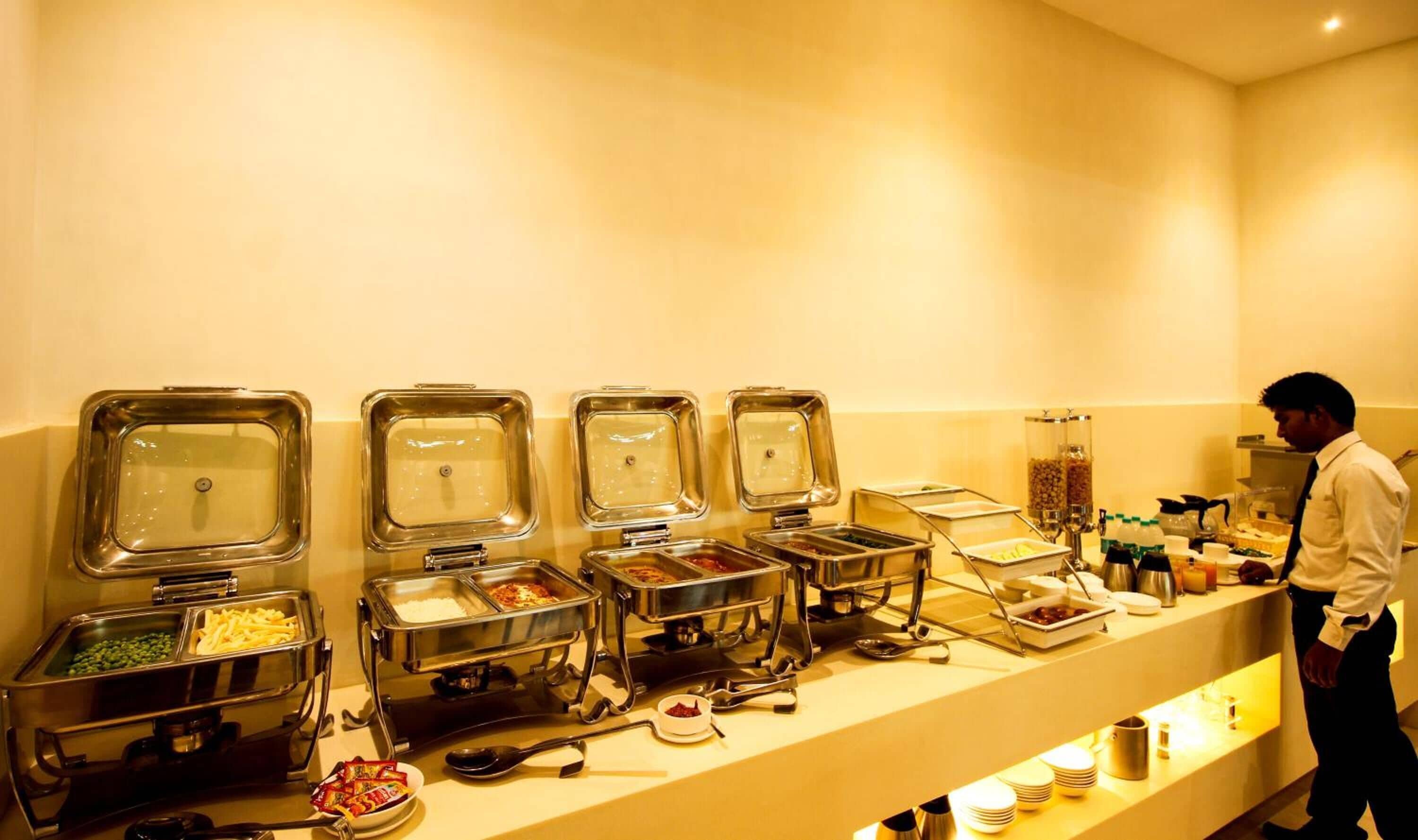 A buffet setup with various food containers and utensils.
