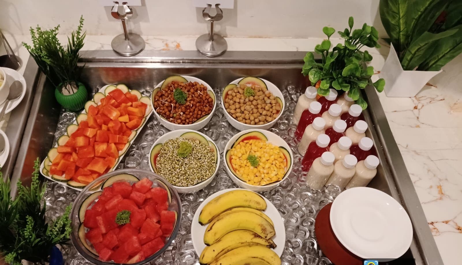 A buffet spread with various fruits, vegetables, and beverages.