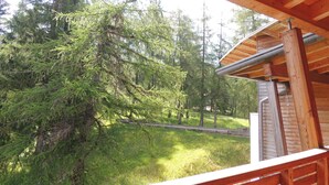Una cabaña de madera con balcón que da a un área boscosa y una vía de tren.