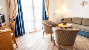 Una habitación de hotel acogedora con un escritorio de madera, televisión, sofá y lámpara.