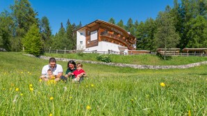 Una familia en un campo, con un edificio al fondo identificado como "IL FALCHETTO".