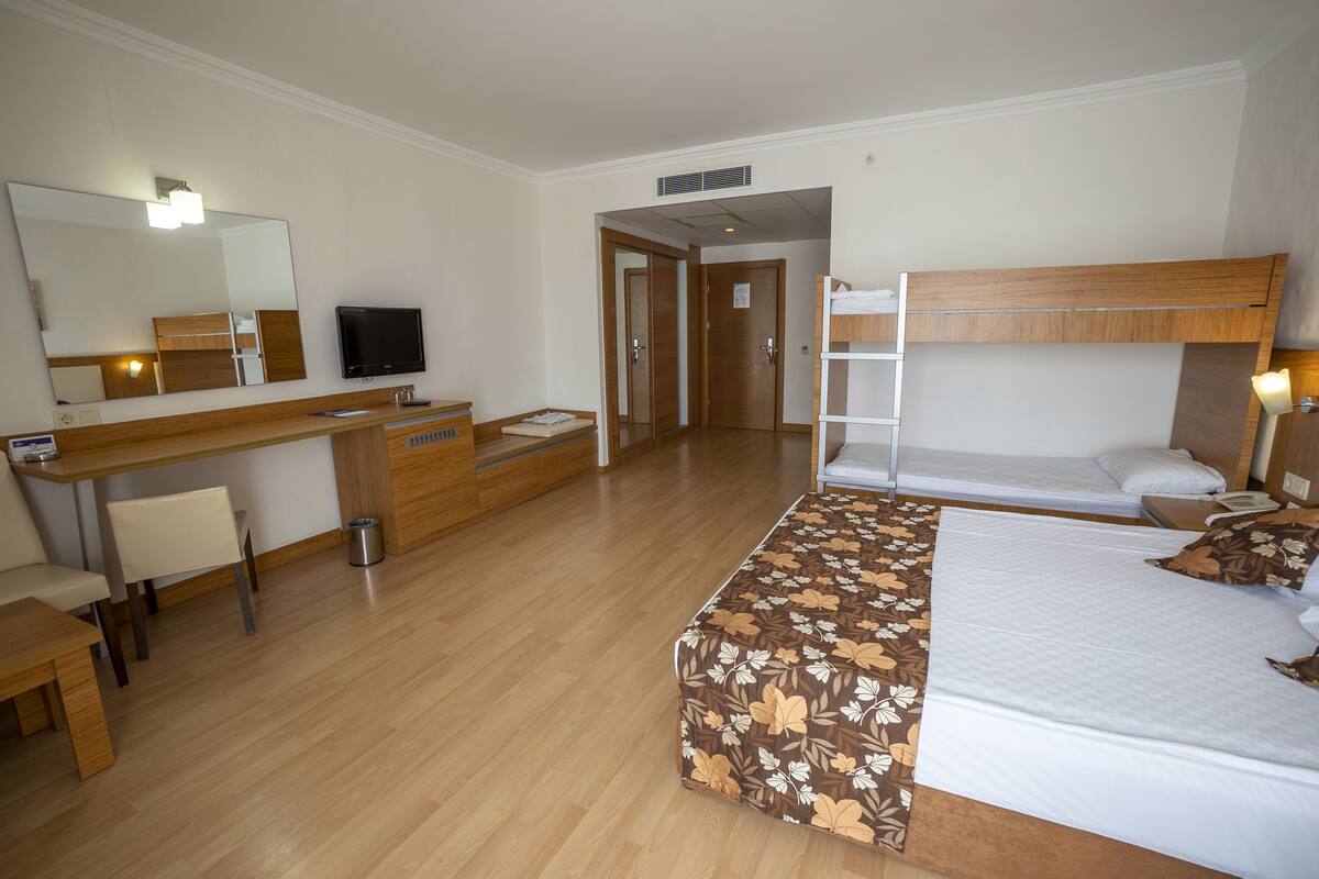 A hotel room with a desk, chair, bed, and a large mirror.