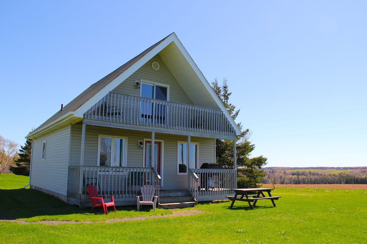 A two-story house with a balcony, a front porch, and a picnic table.