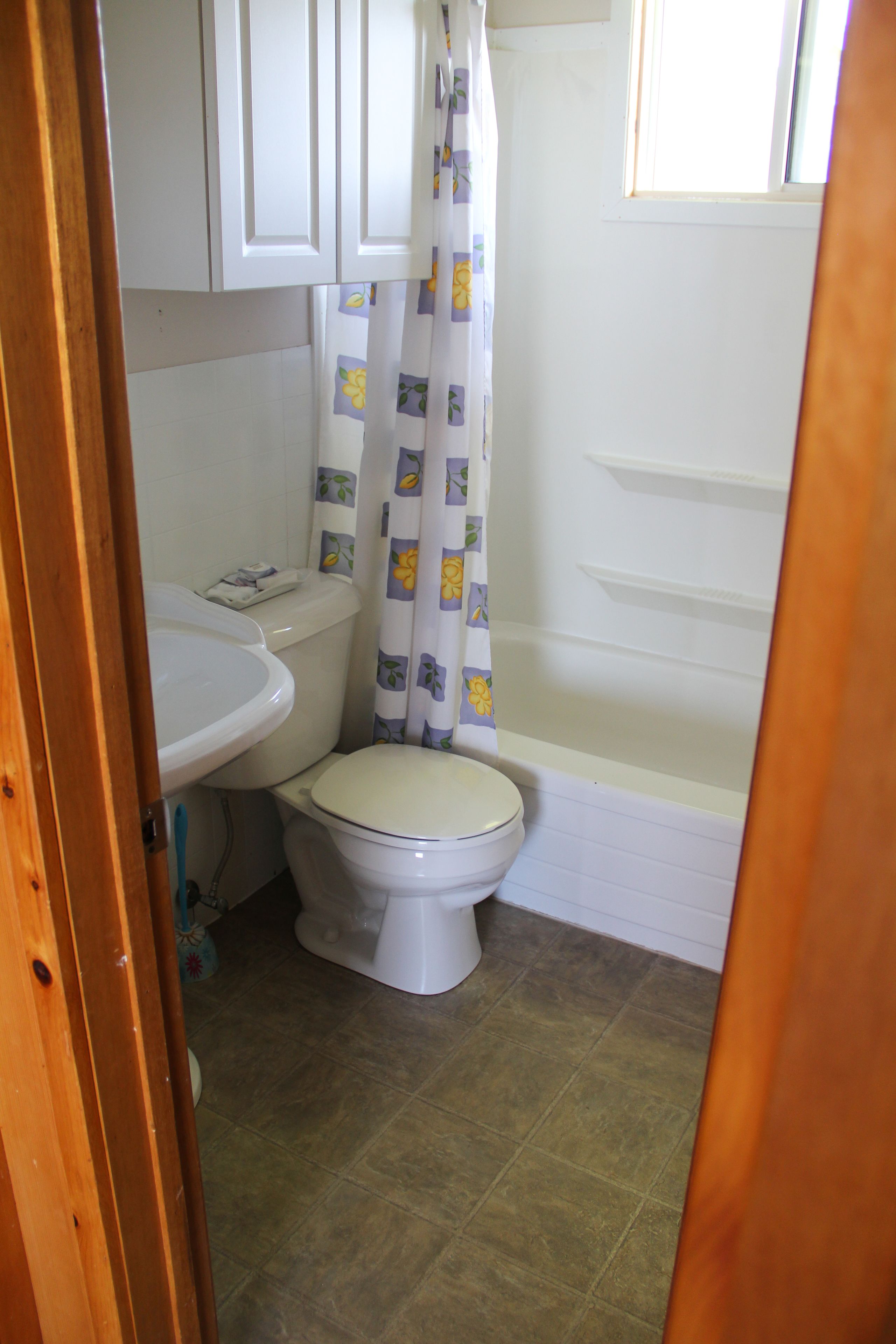 A small bathroom with a toilet, sink, and shower area.