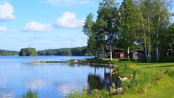 Un chalet au bord du lac, doté d’un quai, et entouré d’une végétation luxuriante et d’arbres.