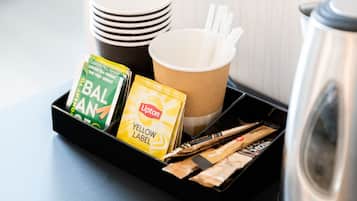 A tray with a coffee maker, paper cups, and Lipton tea bags.