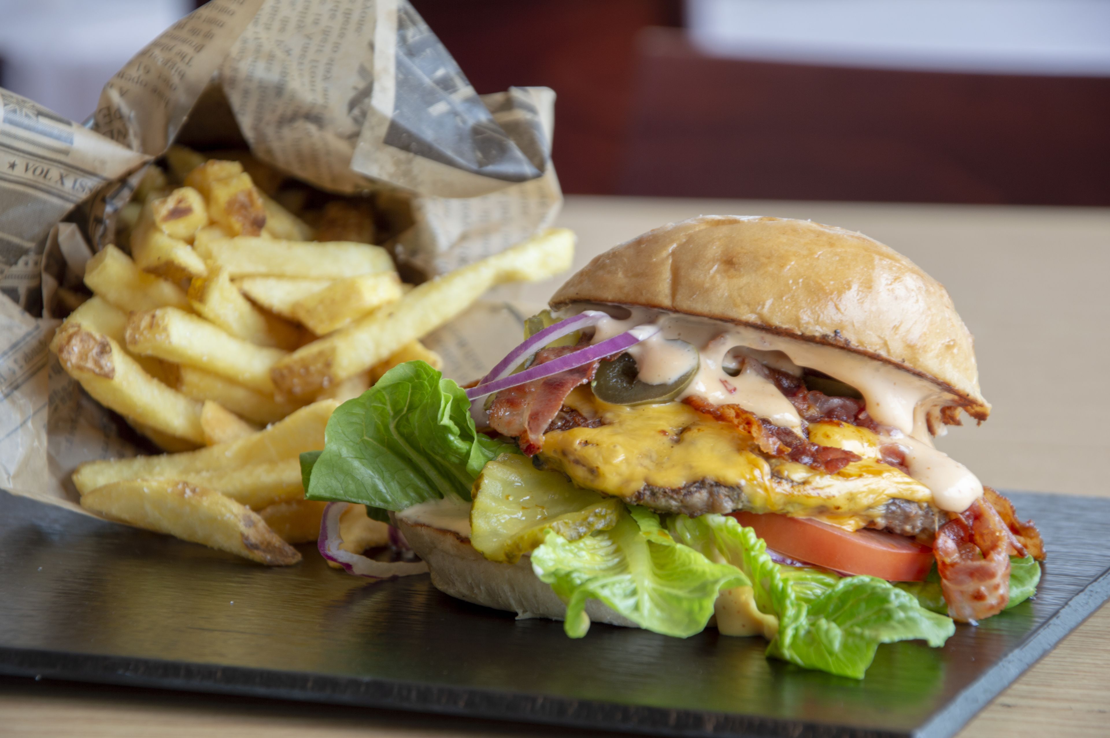A burger with fries on a black plate.