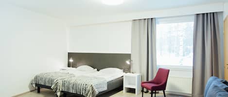 A modern bedroom with a bed, bedside tables, a chair, a sofa, and a window with curtains.