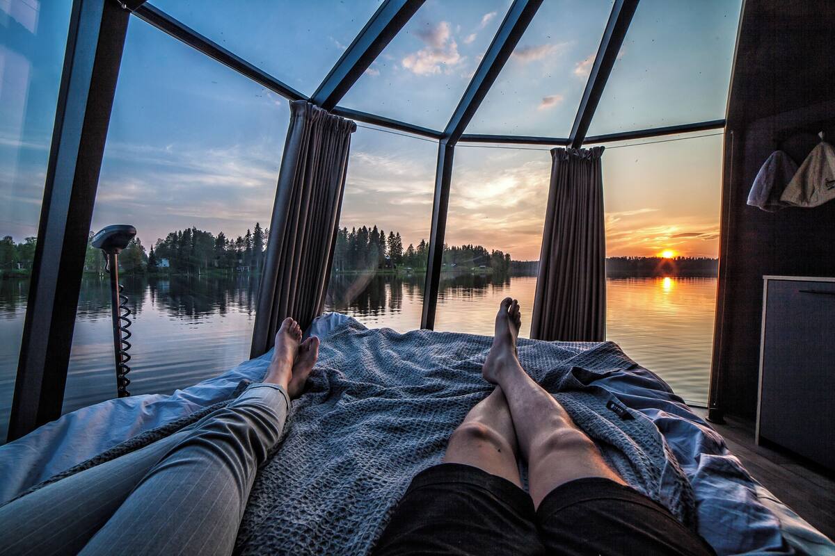 Una habitación con un amplio ventanal que da a una masa de agua al atardecer.