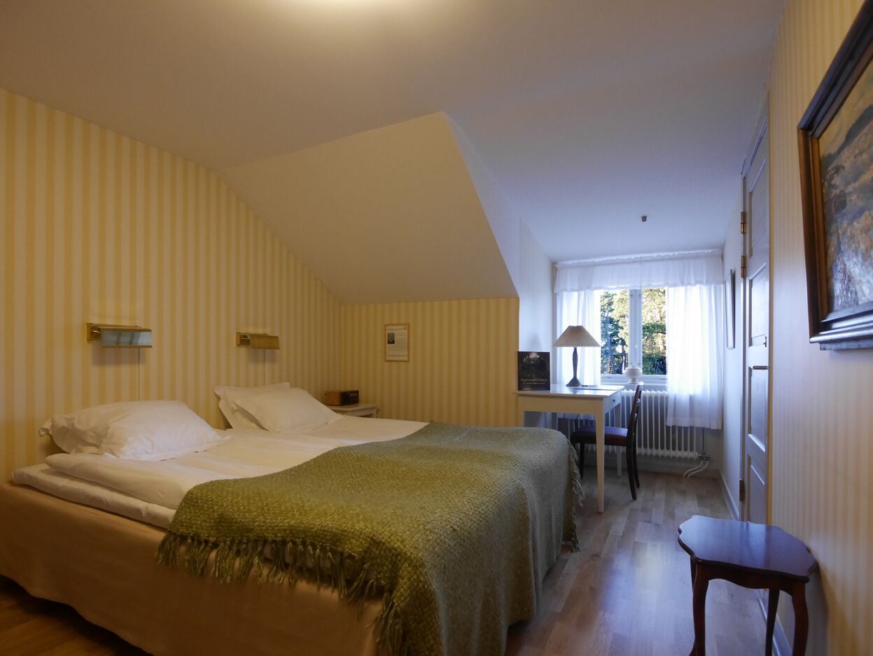 A hotel room with two beds, a desk, and a chair.