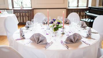 Une table ronde dressée pour un événement formel, avec une nappe blanche, des serviettes grises et un centre de table floral.