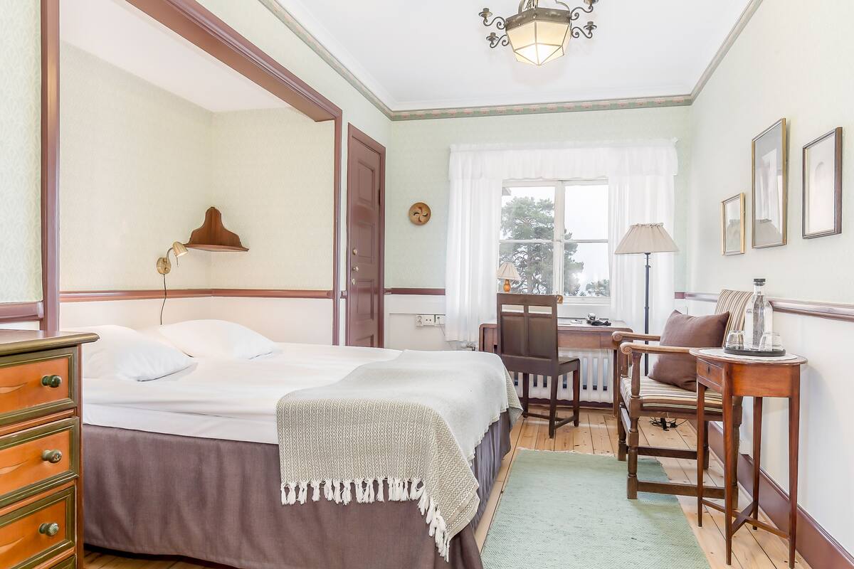 Een slaapkamer met een tweepersoonsbed, een bureau, een stoel en een dressoir.