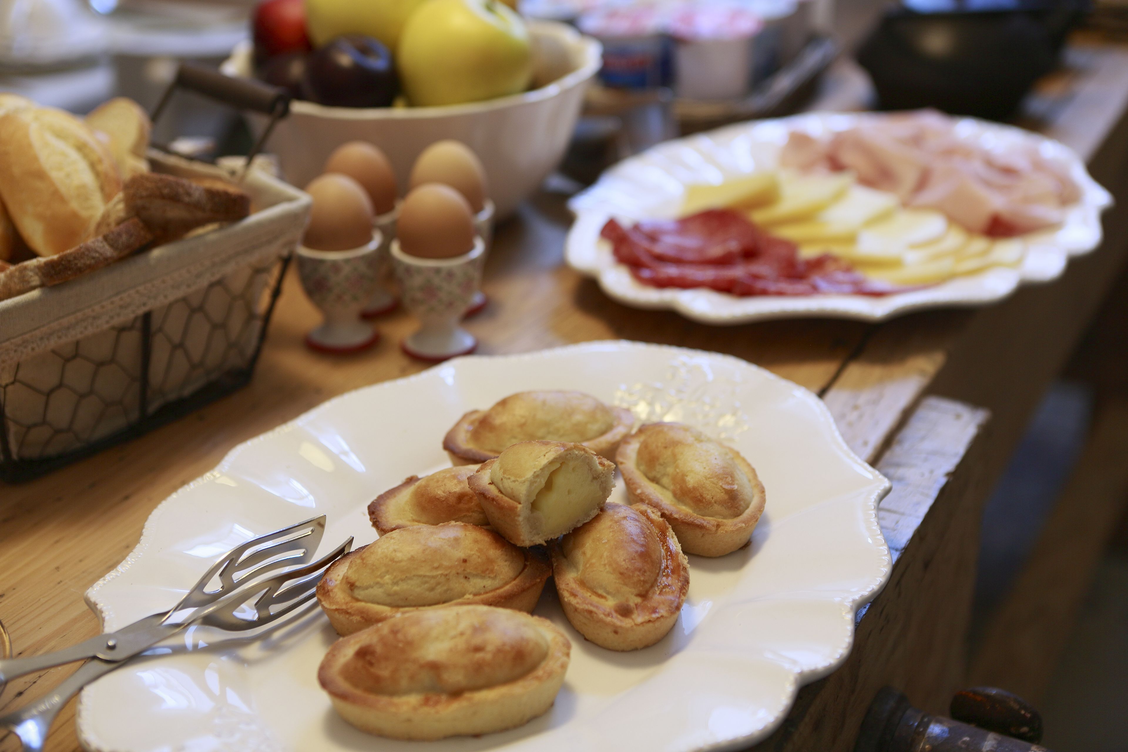 Een ontbijttafel met diverse soorten eten, zoals eieren, brood en gebak.