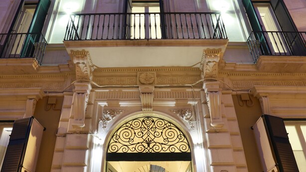 A grand entrance with a decorative archway, a staircase leading to the upper floor, and a small table with chairs outside.