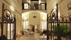 A spacious interior with a high ceiling, a central open area with tables and chairs, and a balcony overlooking the space.