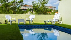 Ein Pool mit weißen Liegestühlen und einer grünen Wand.