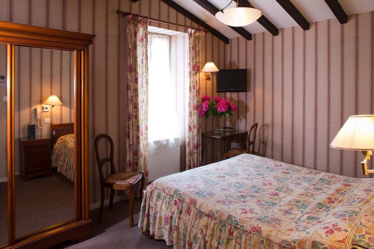 A bedroom with a bed, a desk, a chair, a television, and a mirror.