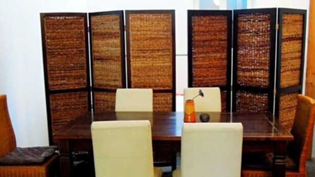 A conference room with a wooden table, white chairs, and a decorative partition with a woven pattern. -  Hostel Bregenz  (Bregenz)