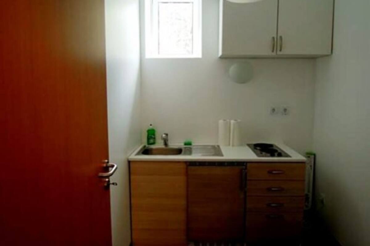 A small kitchenette with a sink, a window, and cabinets.