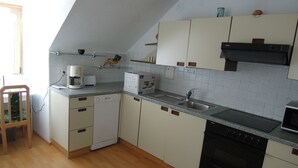 A compact kitchen with white cabinets, a dishwasher, a stove, and a sink. -  Hostel Bregenz  (Bregenz)