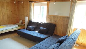 A wooden cabin with a large bed, a sofa, and a small table. -  Hostel Bregenz  (Bregenz)