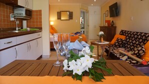 Un salón acogedor con una mesa de madera, dos copas de vino y un ramo de flores blancas.