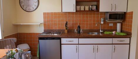 Een kleine keuken met een vaatwasser, magnetron en een klok aan de muur.