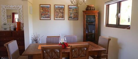 Un coin repas avec une table et des chaises en bois, un lustre et trois tableaux encadrés accrochés au mur.
