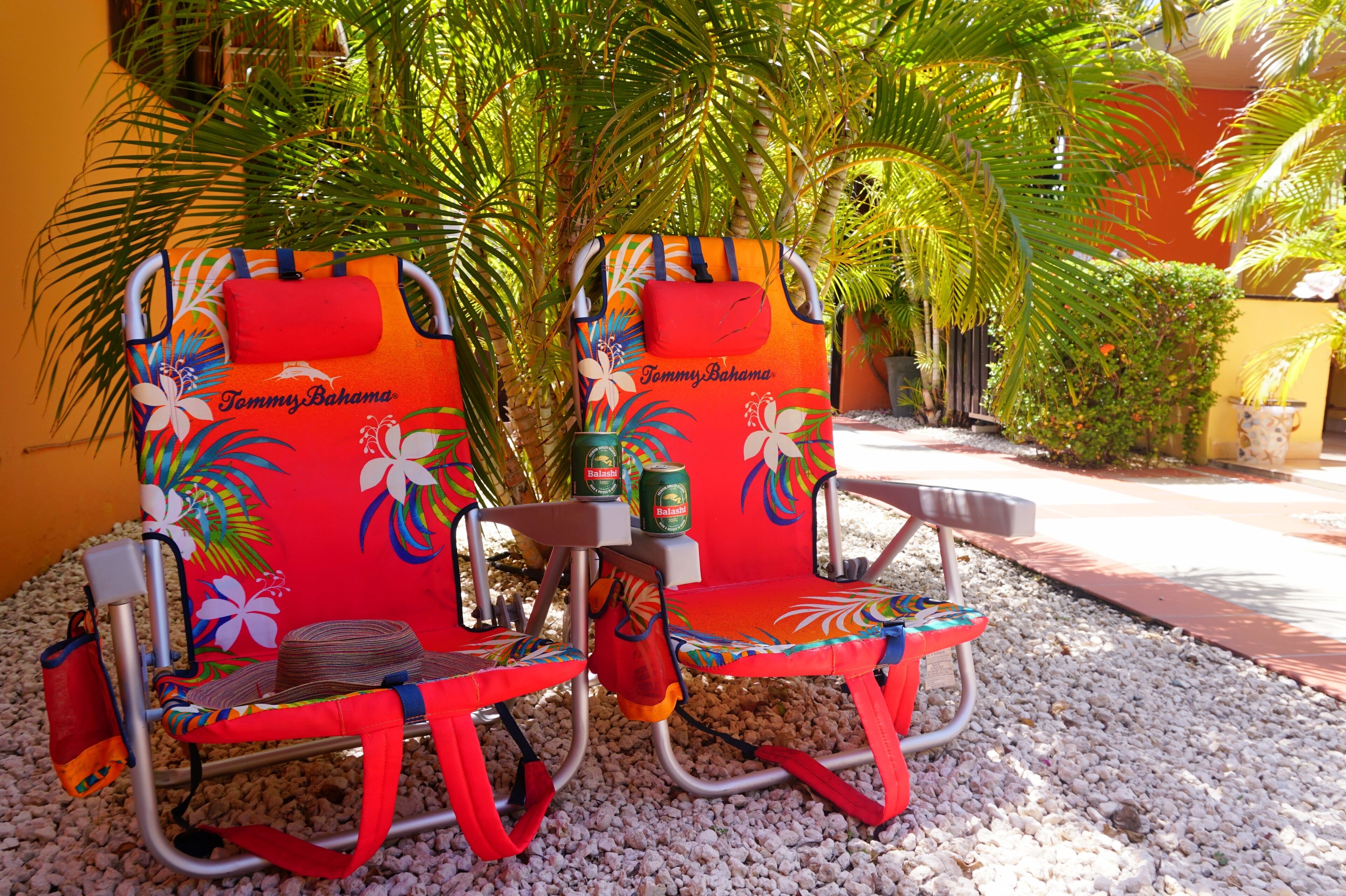 Two beach chairs with a tropical design, a small table, and a potted plant.
