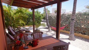 Un patio al aire libre con una mesa de madera, sillas y una hamaca.