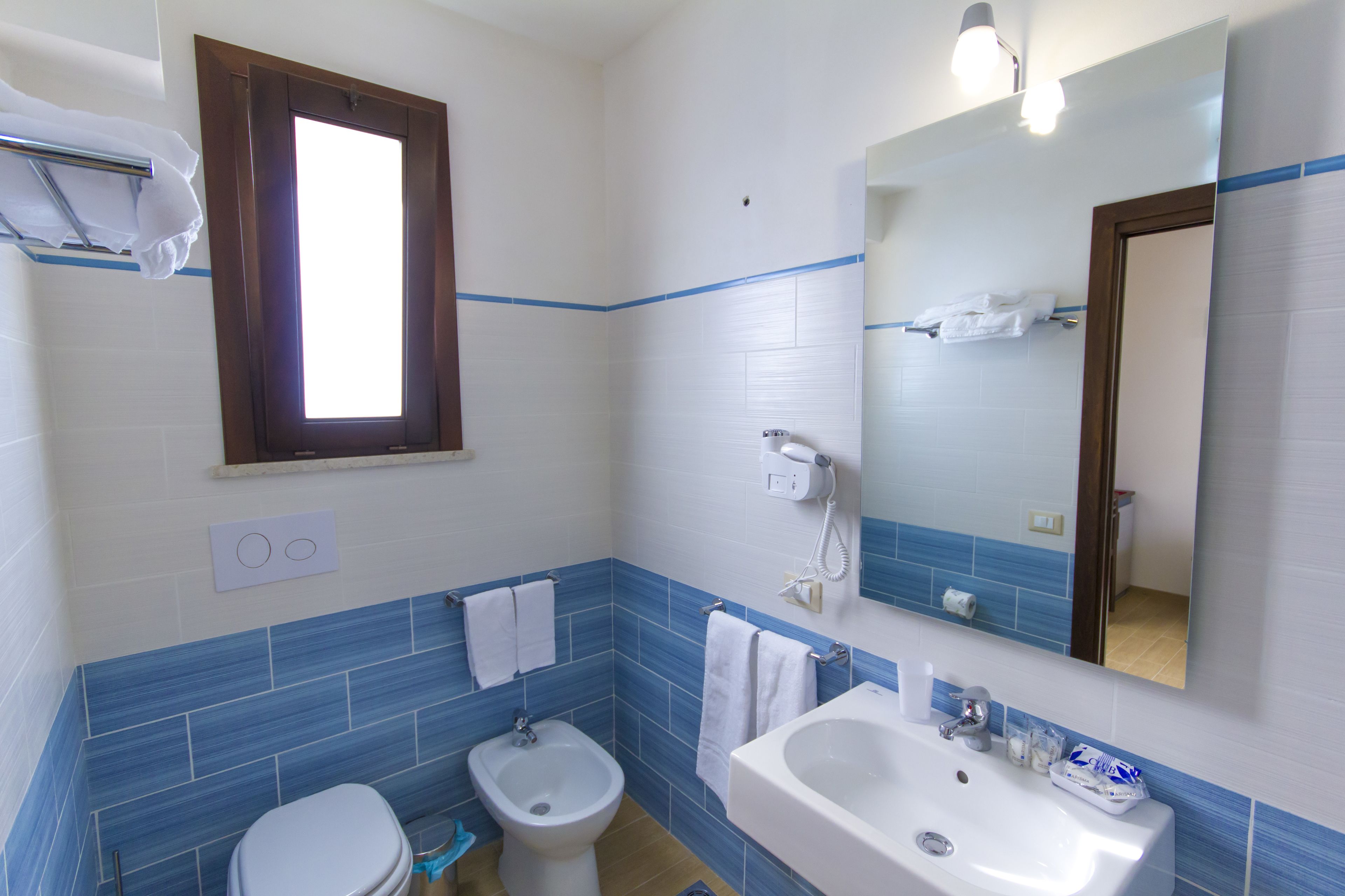 A bathroom with a toilet, bidet, sink, and a mirror.