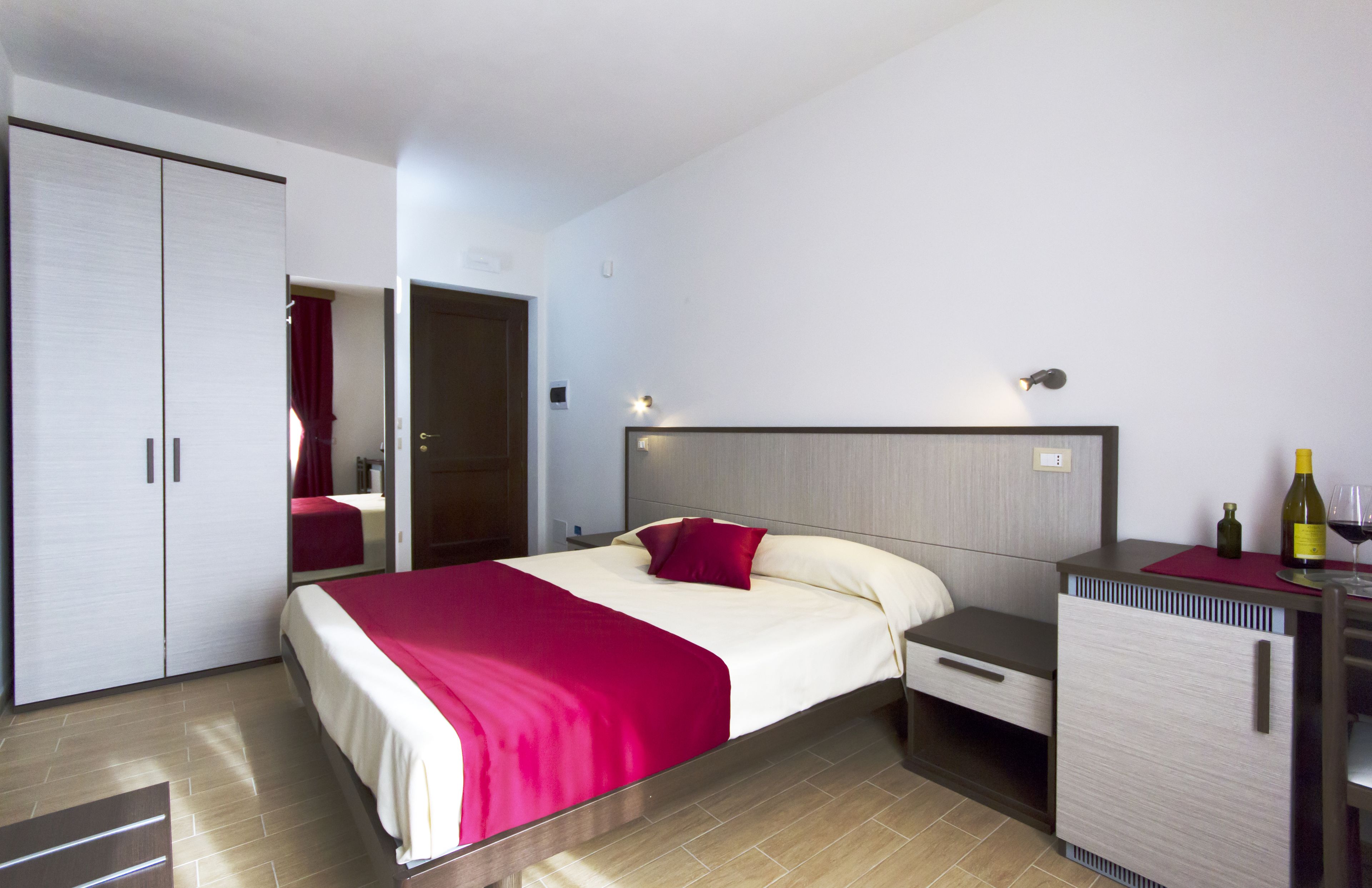 Quarto de hotel com cama, escrivaninha, armário e minibar.