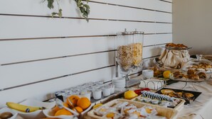 A buffet with various food items and beverages, including fruits, pastries, and containers of yogurt. - Resort Santa Maria (Marsala)