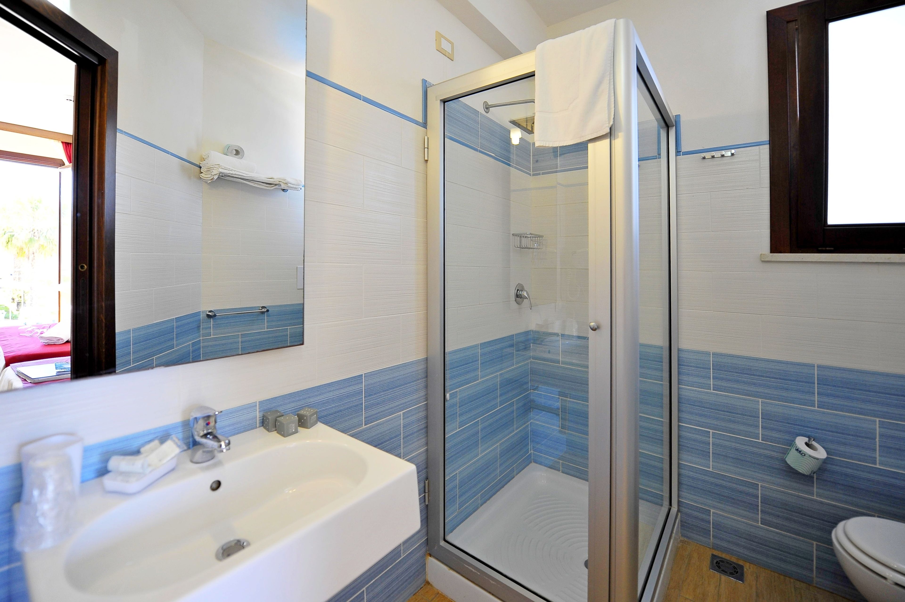 Een badkamer met een glazen douchecabine, een wastafel en een toilet.