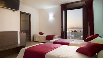 A hotel room with two beds, a TV, a wardrobe, and a balcony with a view.
