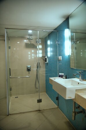 A modern bathroom with a glass-enclosed shower, a white sink, and a blue-tiled wall.