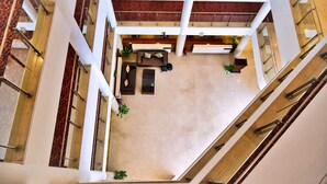 Ein großzügiger Innenhof mit hoher Decke, mehreren Ebenen und einer zentralen Lounge-Ecke.