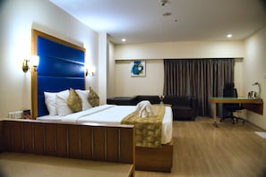 A hotel room with a bed, a desk, a chair, and a couch.