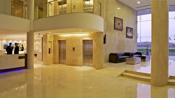 Eine geräumige Lobby mit Empfangsschalter, Sitzbereich und Blick ins Freie.