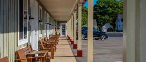 Un motel con filas de sillas y mesas de madera bajo un techo cubierto.