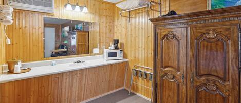 A wooden-paneled bathroom with a sink, mirror, and a cabinet.