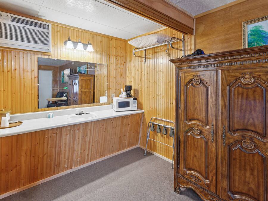 A wooden-paneled bathroom with a sink, mirror, and a cabinet.