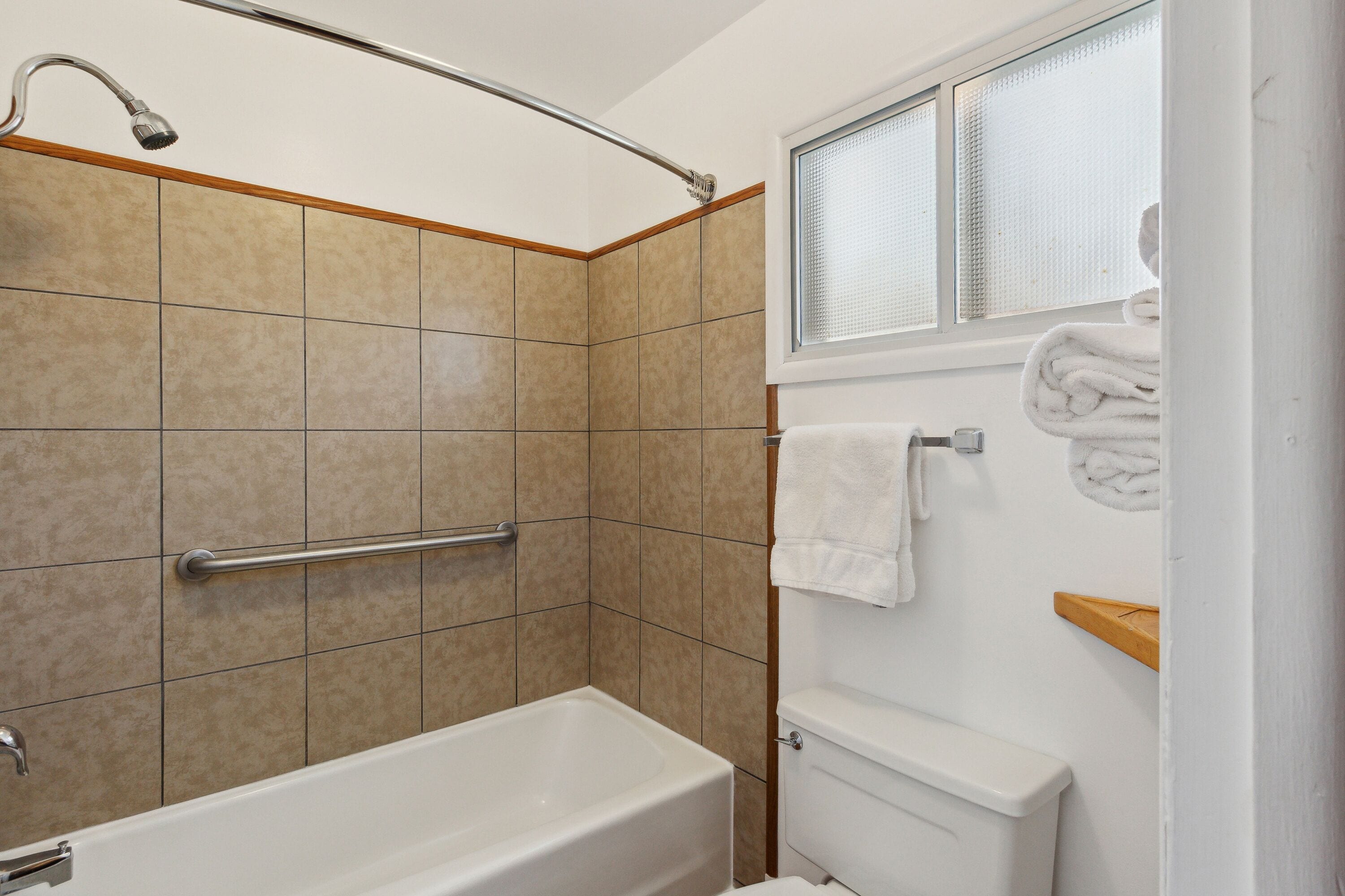 A bathroom with a bathtub, a shower area, and a toilet.