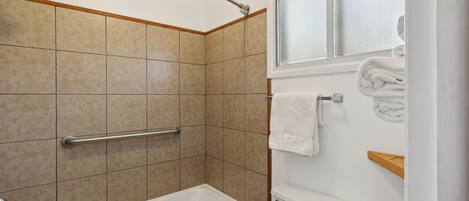 A bathroom with a bathtub, a shower area, and a toilet.
