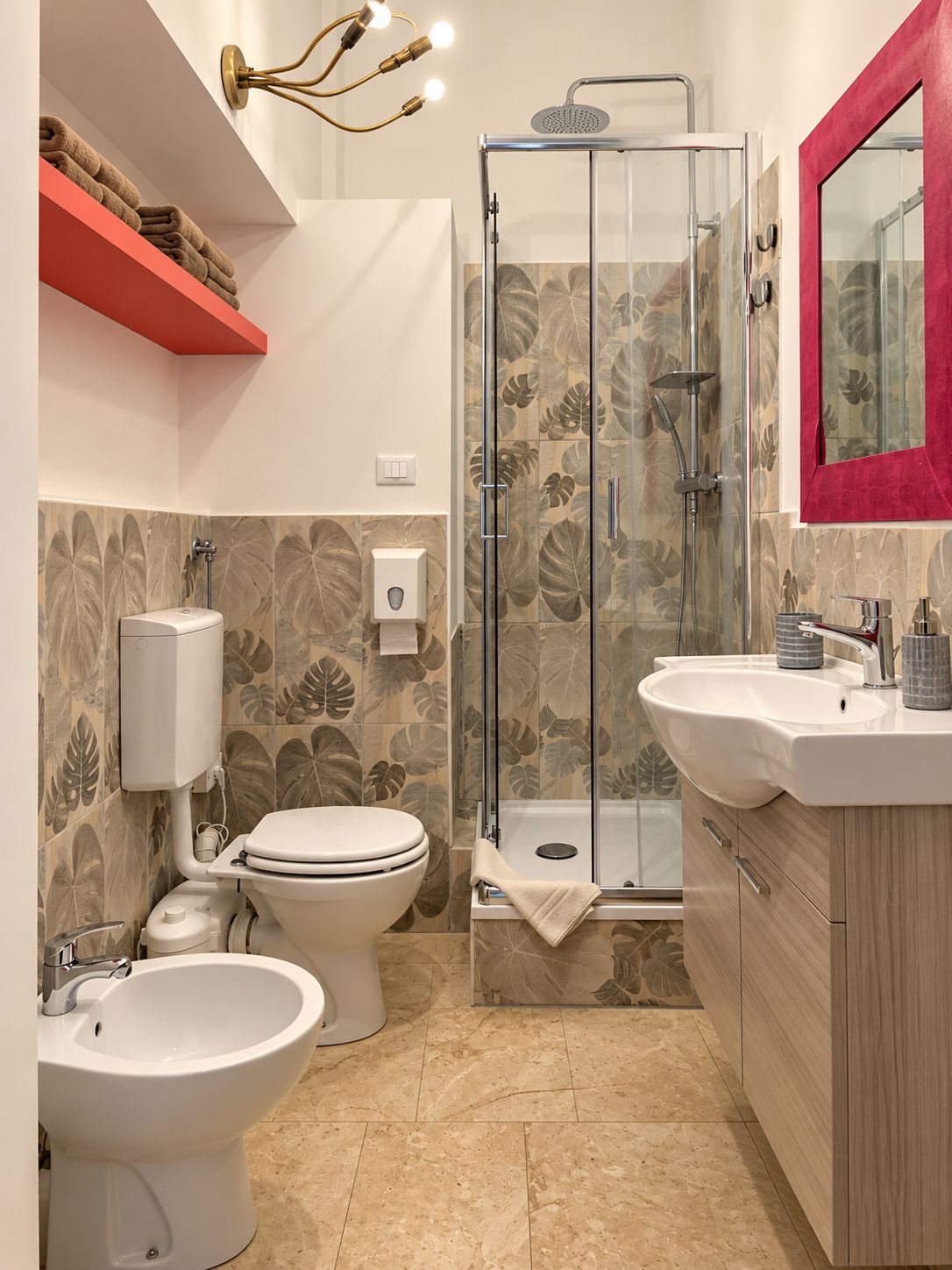Une salle de bain équipée de toilettes, d’un bidet et d’une douche avec des portes en verre.