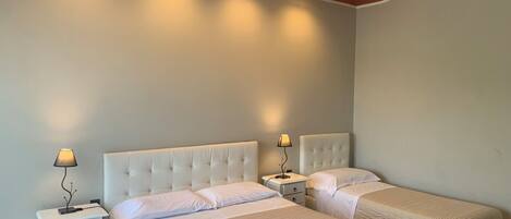A bedroom with two beds, a wooden ceiling, and bedside lamps.